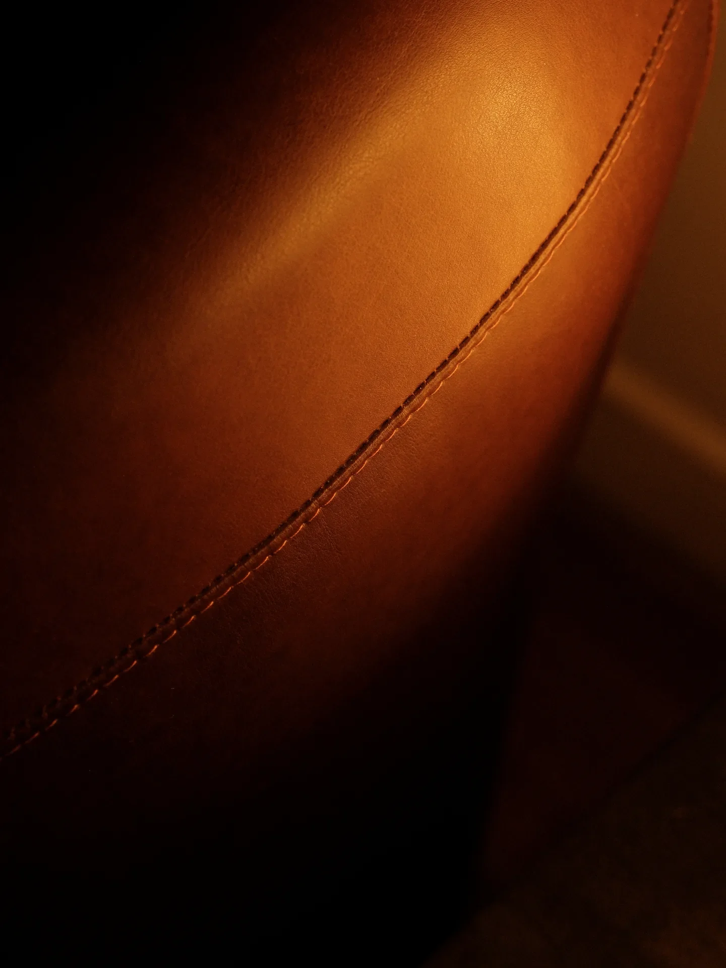 Couture du cuir cognac, finition d’un fauteuil sur mesure